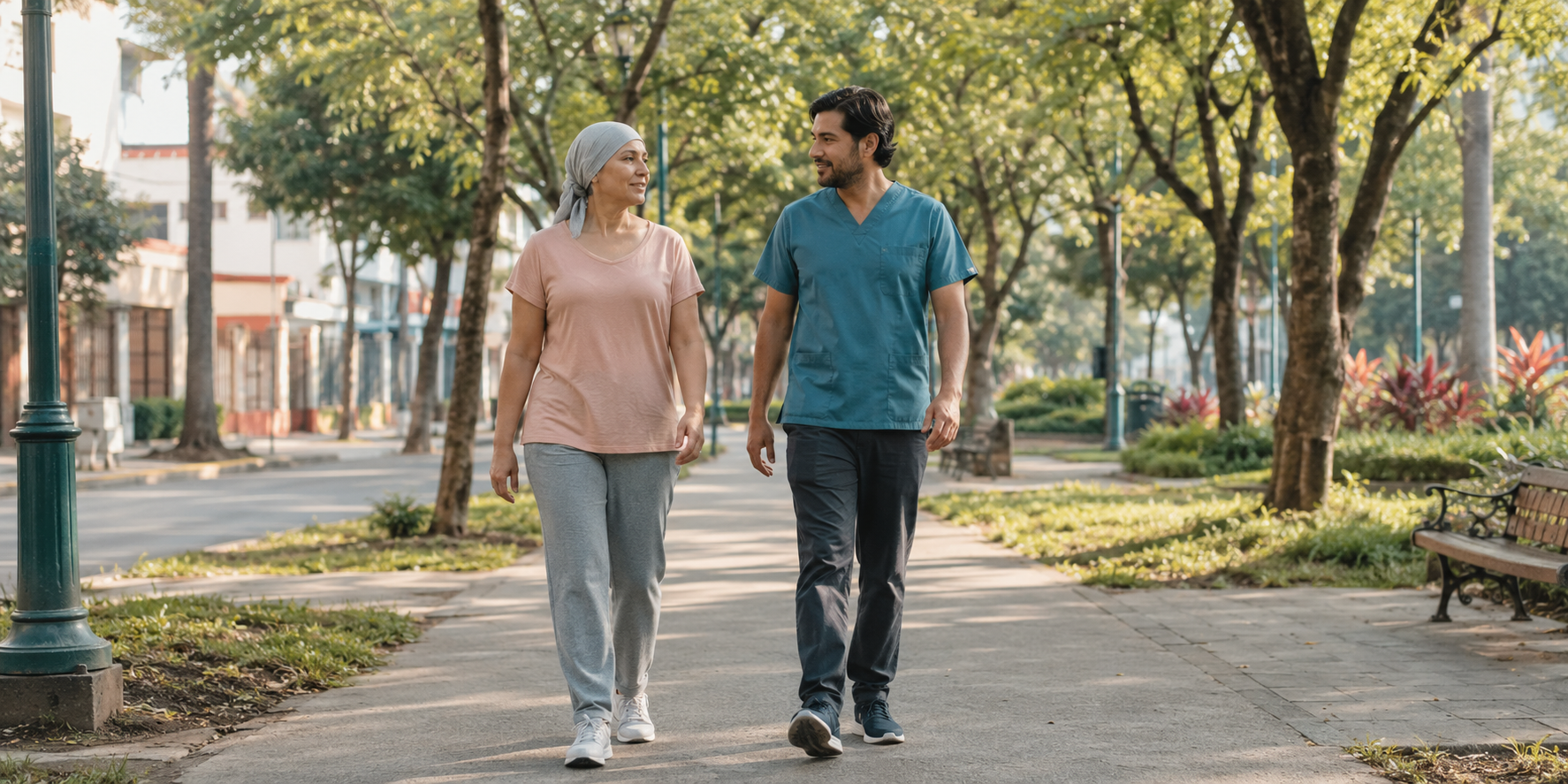 Paciente oncológica caminando por un parque junto a un profesional de rehabilitación